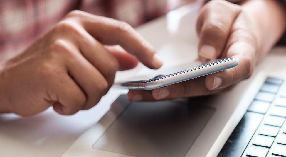 Hands holding a phone in front of a computer keyboard