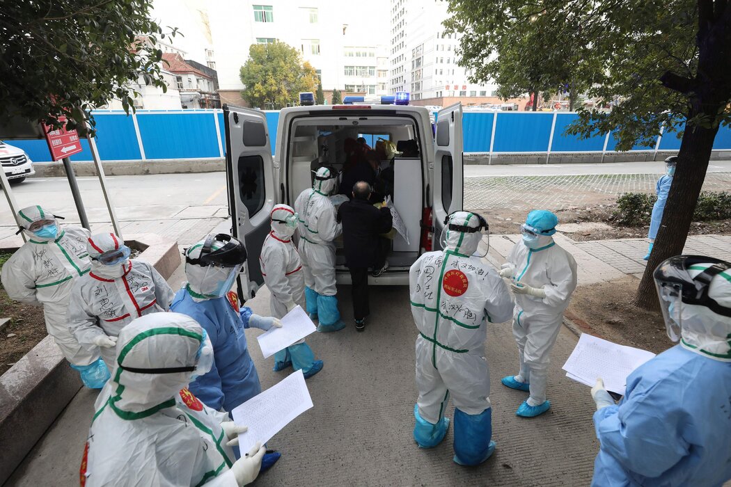 2020年3月,医护人员在中国武汉协助一名新冠肺炎患者登上救护车。 2020年3月,医护人员在中国武汉协助一名新冠肺炎患者登上救护车。