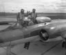 Two members of the Royal Canadian Airforce pose with a fighter jet in a black and white photo.