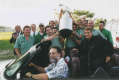 A group of men, some of which who are sitting in a convertible car, holding up the Stanley Cup.