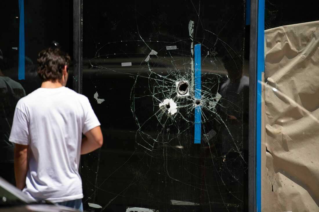 A pedestrian walks past bullet holes in the window of a store front on South Street in Philadelphia, Pennsylvania, on June 5, 2022.