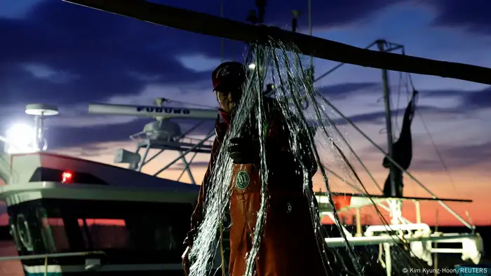 Haruo Ono, a 71-year-old fisherman, works on his boat at dawn. 