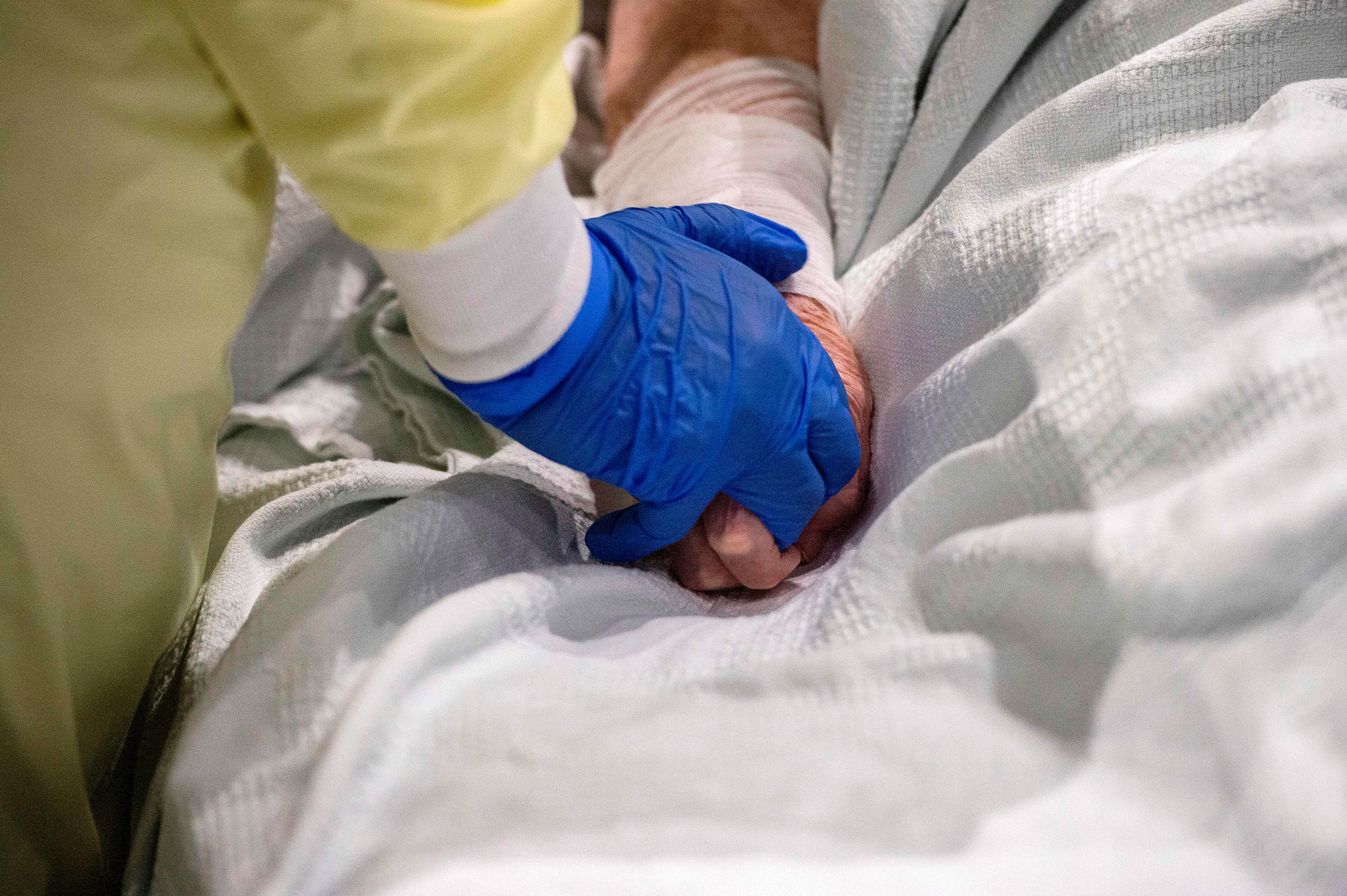 A medical worker cares for and comforts a patient who is suffering from Covid-19 at UMASS Memorial DCU Center Field Hospital in Worcester, Massachusetts, on January 13.