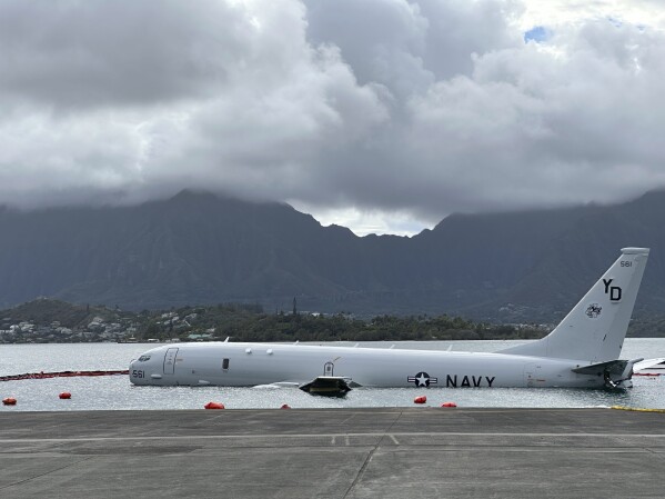 A Navy P-8A plane that overshot a runway at Marine Corps Base Hawaii and landed in shallow water offshore sits on a reef and sand in Kaneohe Bay, Hawaii, on Monday, Nov. 27, 2023. The U.S. Navy said Monday that it has removed nearly all of the fuel from the large plane that landed in an environmentally sensitive bay, but it doesn't have a timetable for when it will get the aircraft out of the water. (AP Photo/Audrey McAvoy)