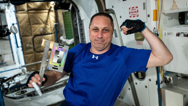 Russian cosmonaut Anton Shkaplerov poses with a ruler and color chart for a space archaeology experiment.