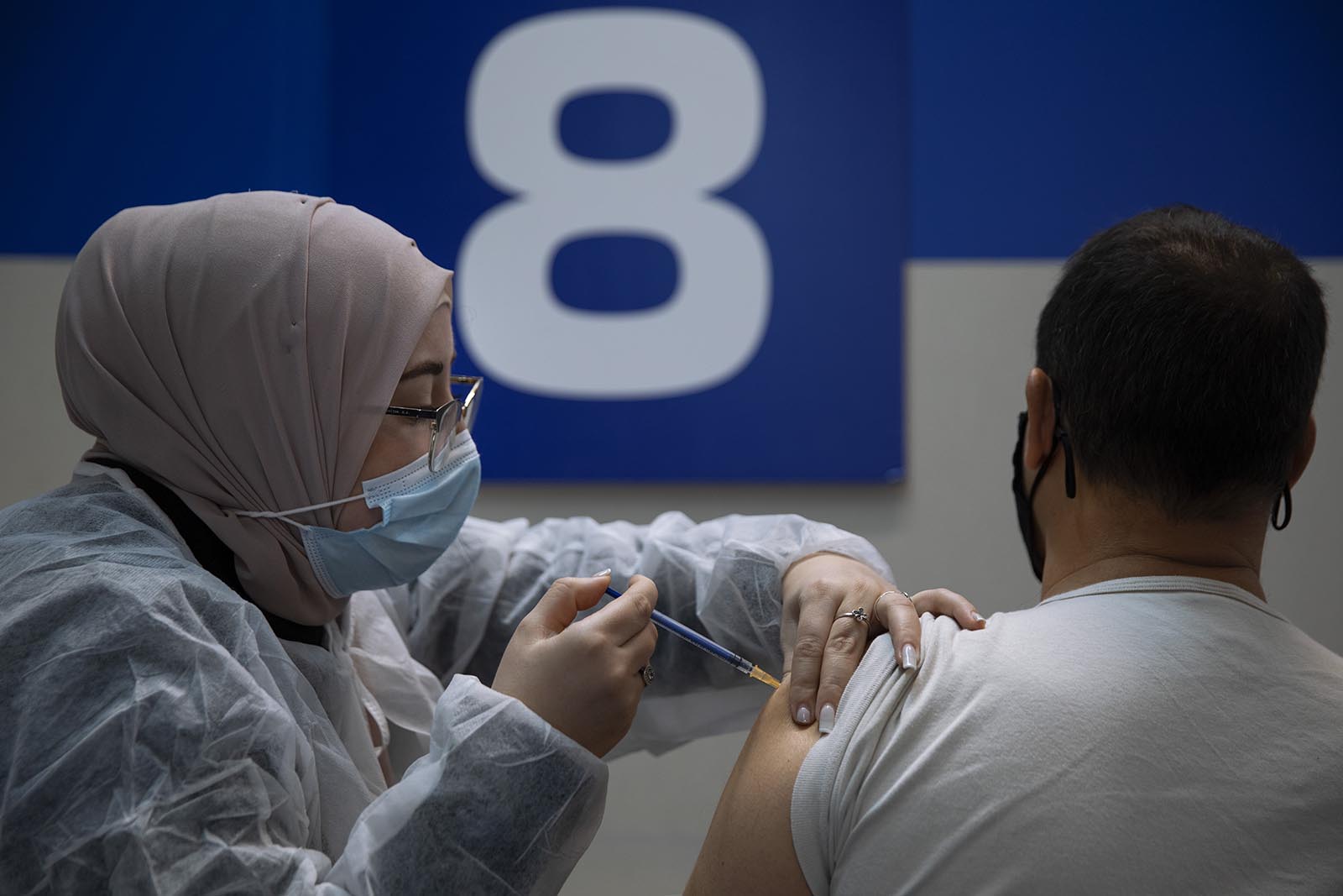 An Israeli man receives his second Pfizer-BioNTech Covid-19 vaccine from a medical professional at a vaccination center set up on a mall parking lot in Givataim, Israel, on Wednesday, January 20.