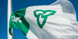 The Franco-Ontarian flag flying against the backdrop of a clear blue sky.