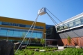 he James K. Bartleman Centre on a sunny day. There are plants and landscaping décor in the foreground and a piece of public art is prominent. 