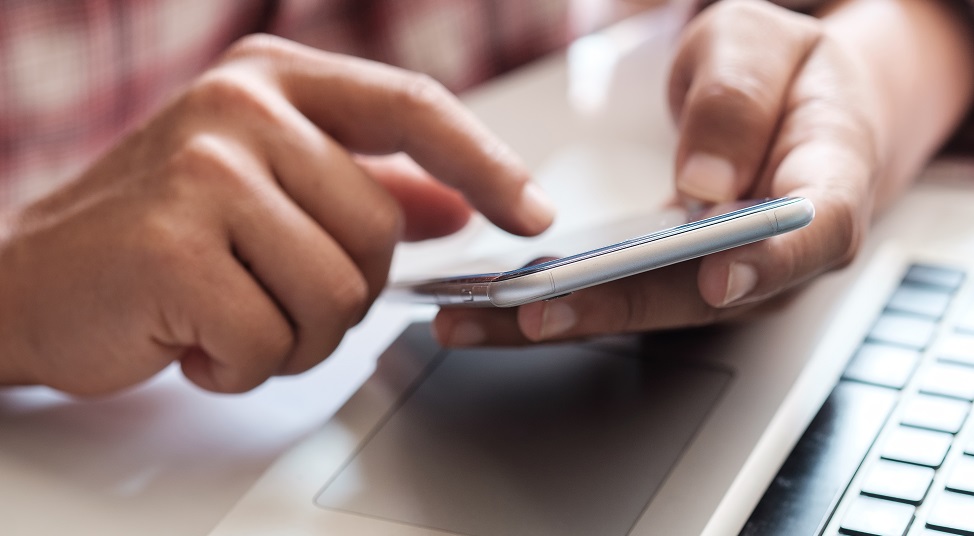 Hands holding a phone in front of a computer keyboard