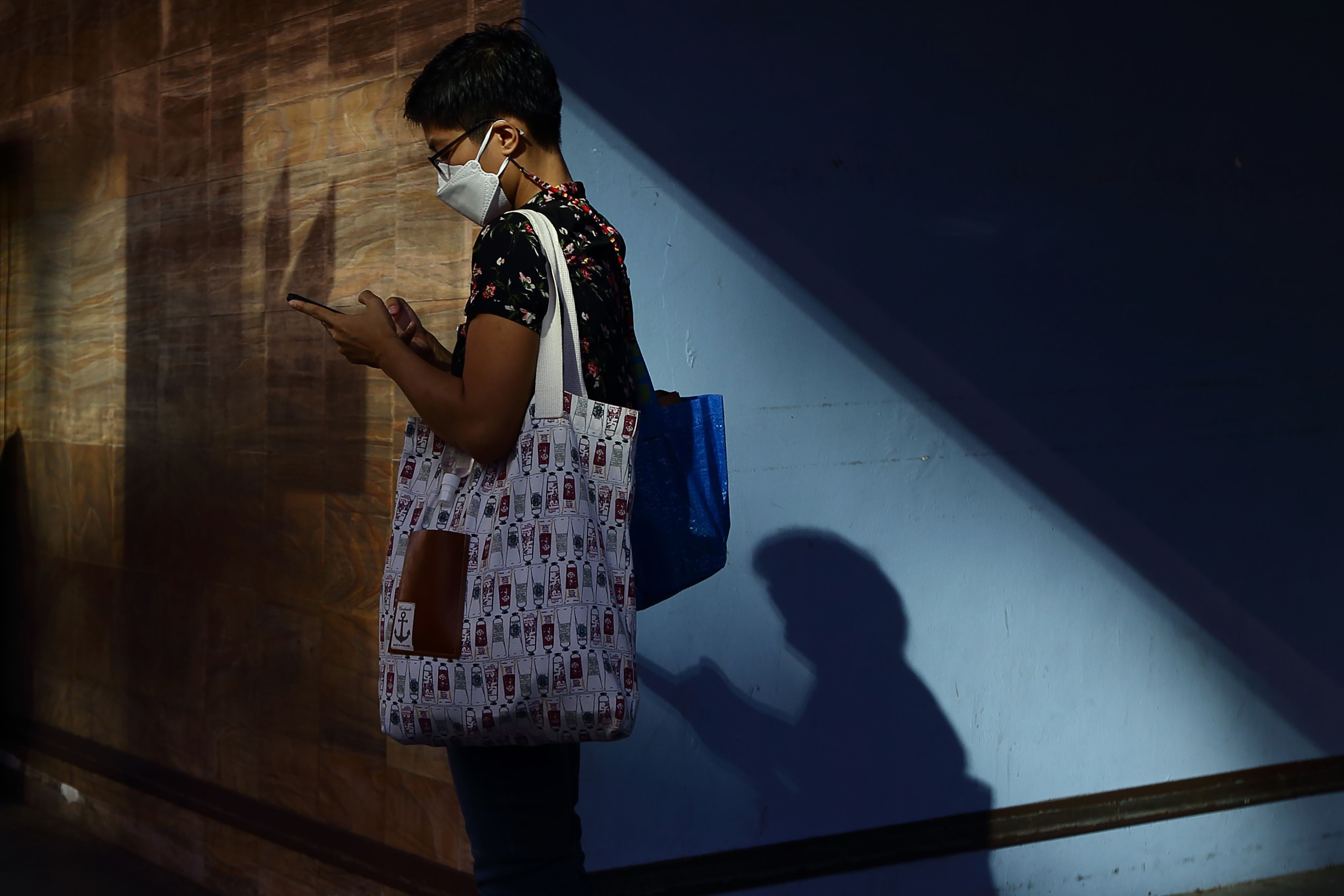 A woman wearing protective mask uses her mobile phone while waiting for a bus on January 13 in Singapore.