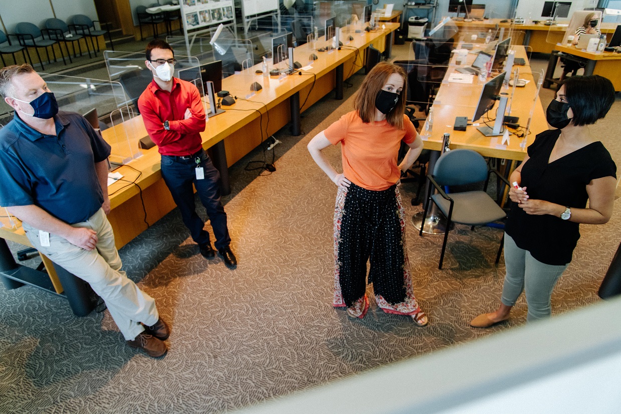 Four people standing in a meeting room having a discussion