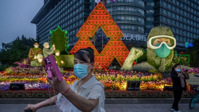 A woman takes a selfie in front of a display for healthcare workers