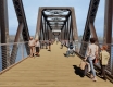 Rendering of pedestrians walking on the new multi-use pathway of the Chief William Commanda Bridge with a blue sky in the background and water beneath.