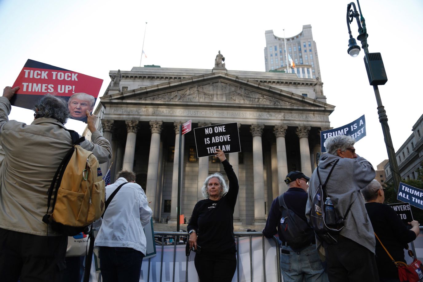 Demonstrators stand outside the court before the start of Trump's civil trial on Monday. 