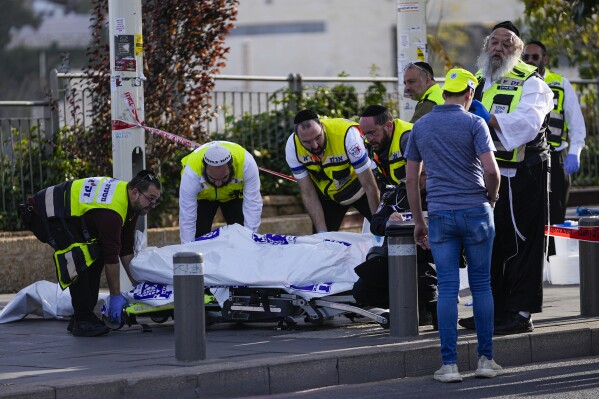 FILE - Volunteers from the Zaka rescue service remove a body killed in the shooting attack in Jerusalem, Thursday, Nov. 30, 2023. The shooting death of an Israeli man who raced to confront Palestinian attackers has raised questions about the use of excessive force among Israeli security forces and the public. The man's shooting mirrors previous incidents where Israeli security forces or civilians have opened fire on attackers who no longer appear to pose a threat or on suspected assailants or unarmed civilians. (AP Photo/Ohad Zwigenberg, File)