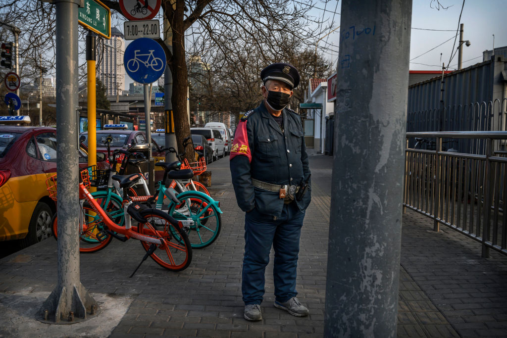 A Chinese transit worker wears a protective mask as he waits at a bus station on February 25, 2020 in Beijing, China. 