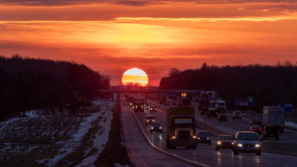 The sun sets over highway 401 traffic during the winter solstice in Belleville, Ont., on Tuesday, December 21, 2021. (THE CANADIAN PRESS/Lars Hagberg)