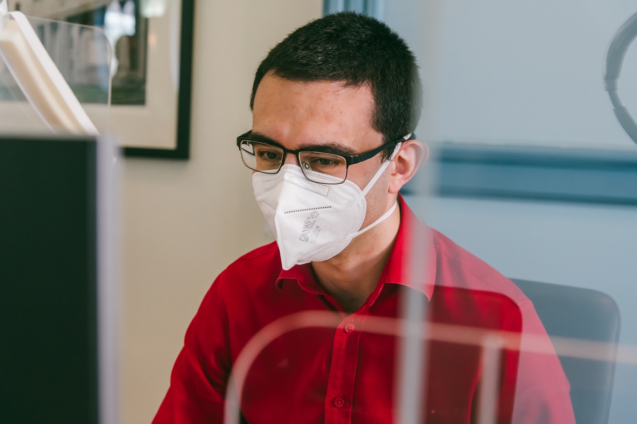 Andres, wearing a mask, working at his computer