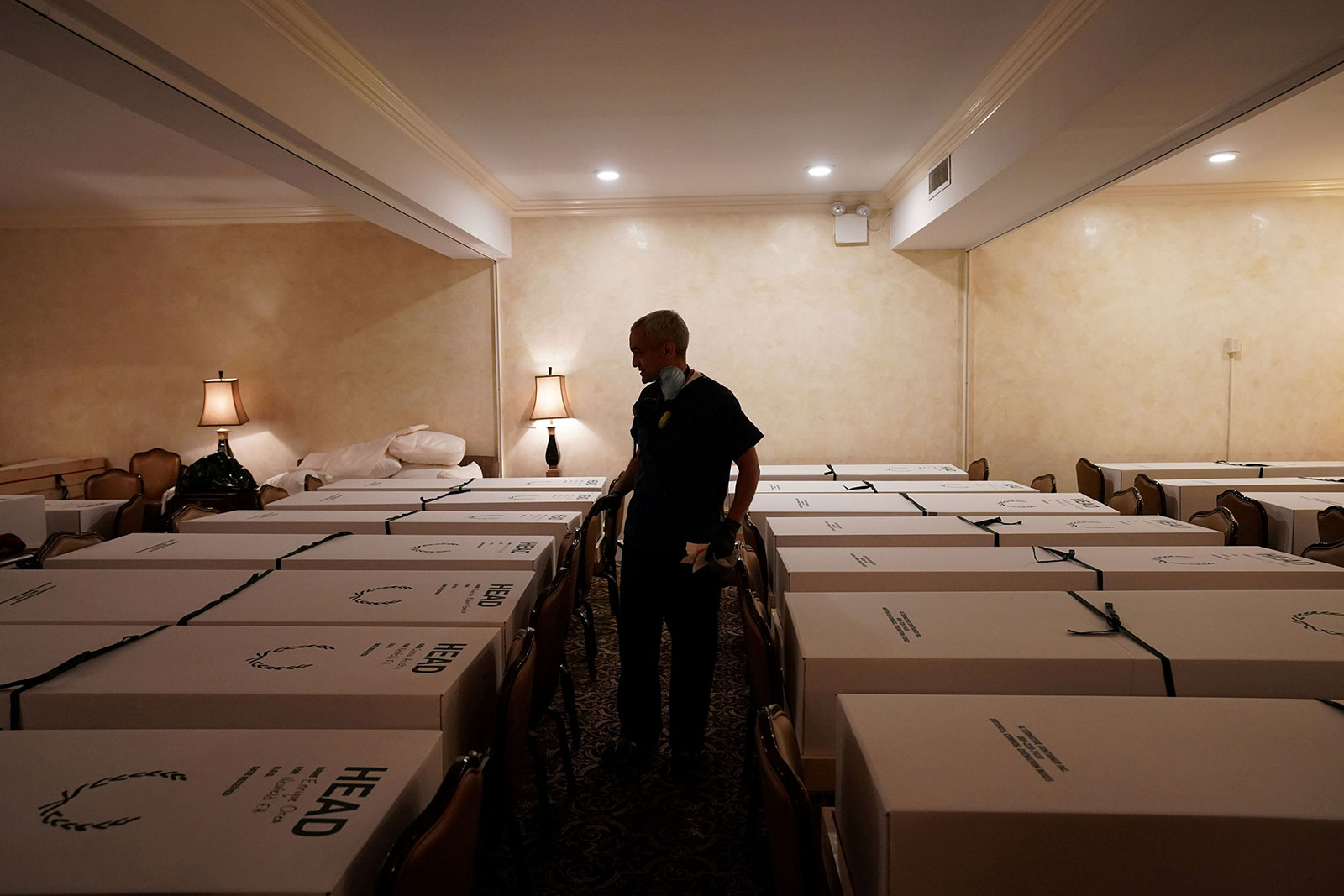 Funeral Director Omar Rodriguez walks by caskets at Gerard J. Neufeld funeral home in Queens, New York, on April 26.