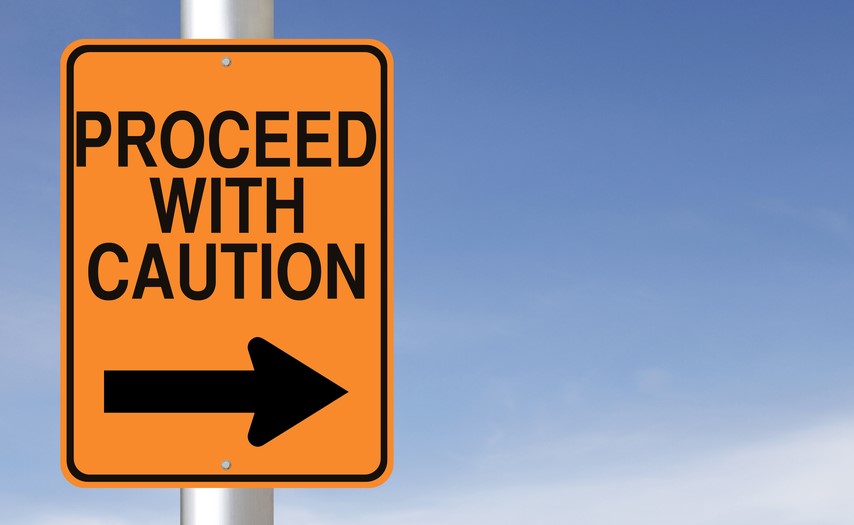 An orange sign that reads “proceed with caution” against a blue background