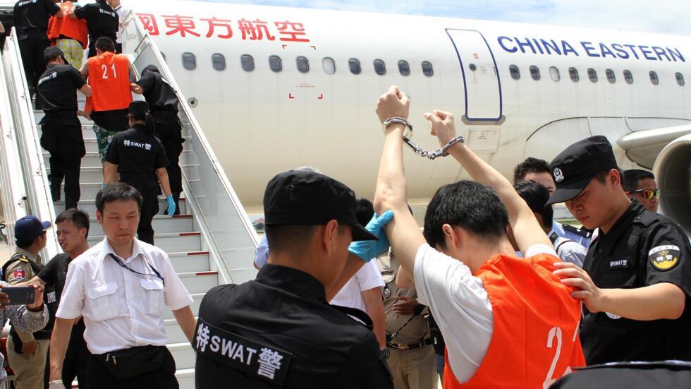 2016年6月24日，在柬埔寨金边国际机场，一名嫌疑人在登机前被中国警察官员检查身体时举起双手。