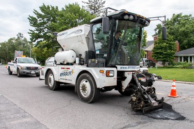 A white Python 5000 machine filling in a pothole. 