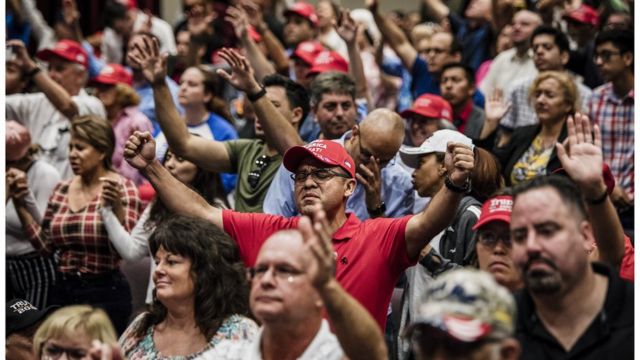 Attendees pray together before President Donald Trump addresses the crowd at the King Jesus International Ministry during a Evangelicals for Trump rally in Miami