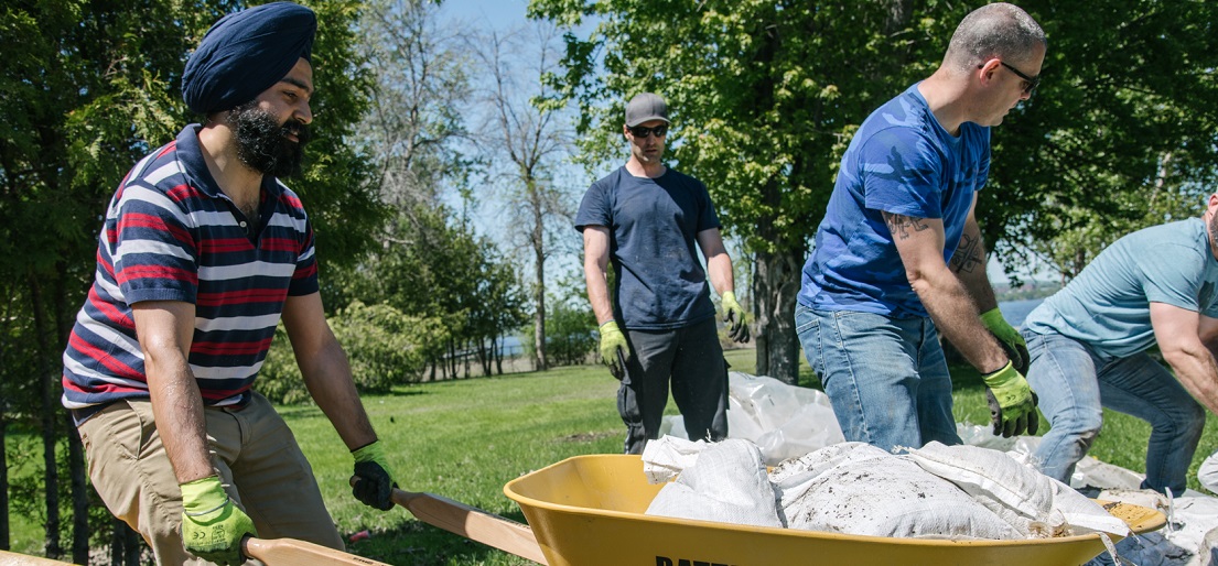 Volunteers move sandbags with a wheelbarrow