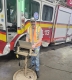 A man working on a laptop in a garage in front of a fire truck / Un homme travaillant sur un ordinateur portable dans un garage, devant un camion de pompiers