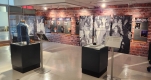 A gallery room filled with display cases, featuring a brick wall with photos from the Ottawa Rocks! – Reunion Tour exhibit.