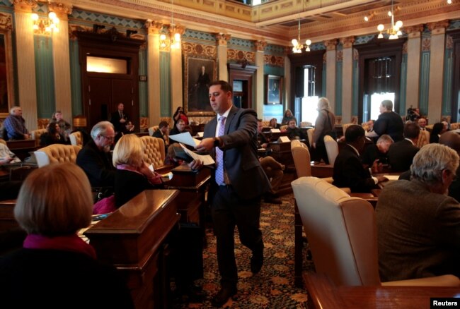 FILE - Ballots are passed out to 16 Electors on the Michigan Senate floor for them to cast their formal votes for the president and vice president of the United States in Lansing, Michigan, U.S., December 19, 2016