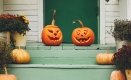 Green painted stairs leading up to a door. The steps are lined with fall planters and small uncarved pumpkins. At the top of the steps, two carved jack-o-lanterns are in the center in front of the door. Escalier peint en vert menant à une porte. Les marches sont bordées de jardinières d’automne et de petites citrouilles non sculptées. En haut des marches, deux citrouilles sculptées se trouvent au centre, devant la porte.