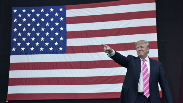 Donald Trump points in front of an American flag Donald Trump points in front of an American flag